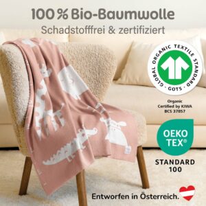 Rosa Babydecke aus Baumwolle über einem Sessel mit Bio-Zertifizierung drapiert – stilvolle baby decke baumwolle, ideal als weiche gestrickte Kuscheldecke fürs Babyzimmer.