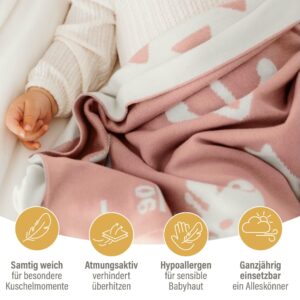 Baby liegt eingekuschelt in einer rosa Babydecke aus Baumwolle – atmungsaktive baby decke baumwolle, besonders weiche gestrickte Kuscheldecke für empfindliche Babyhaut.