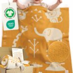 Glückliches Baby liegt unter Babydecke aus Baumwolle in Gelb – gestrickte Babydecke für Kinderwagen, aus zertifizierter Bio-Baumwolle, ideales Geschenk zur Geburt Mädchen und Jungen. GOTS- und OEKO-TEX-zertifiziert mit Geschenkverpackung + Karte.