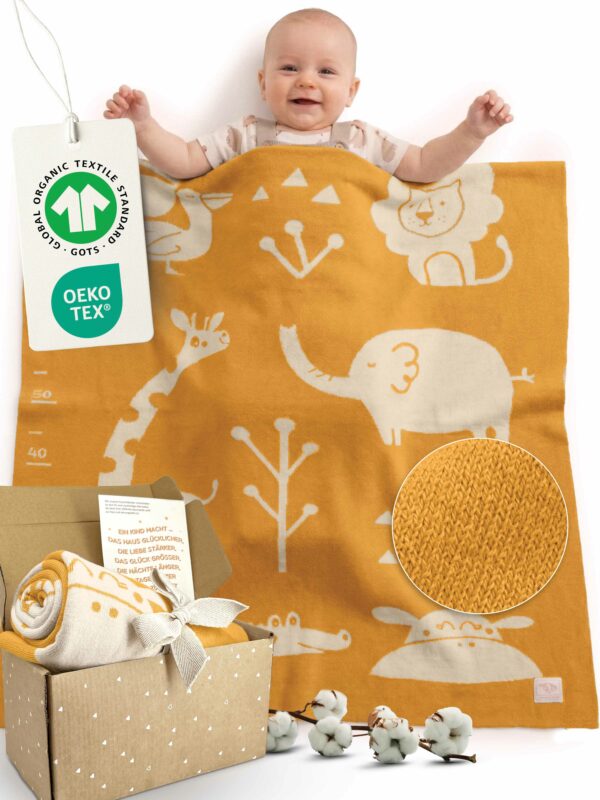 Glückliches Baby liegt unter Babydecke aus Baumwolle in Gelb – gestrickte Babydecke für Kinderwagen, aus zertifizierter Bio-Baumwolle, ideales Geschenk zur Geburt Mädchen und Jungen. GOTS- und OEKO-TEX-zertifiziert mit Geschenkverpackung + Karte.