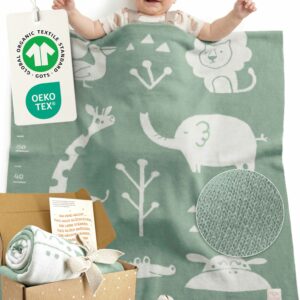 Glückliches Baby liegt unter gestrickter Babydecke, Weiche Babydecke aus Baumwolle in Grün – hochwertige Bio Baumwolle Babydecke mit OEKO-TEX und GOTS Zertifizierung, ideales Geschenk für Neugeborene.