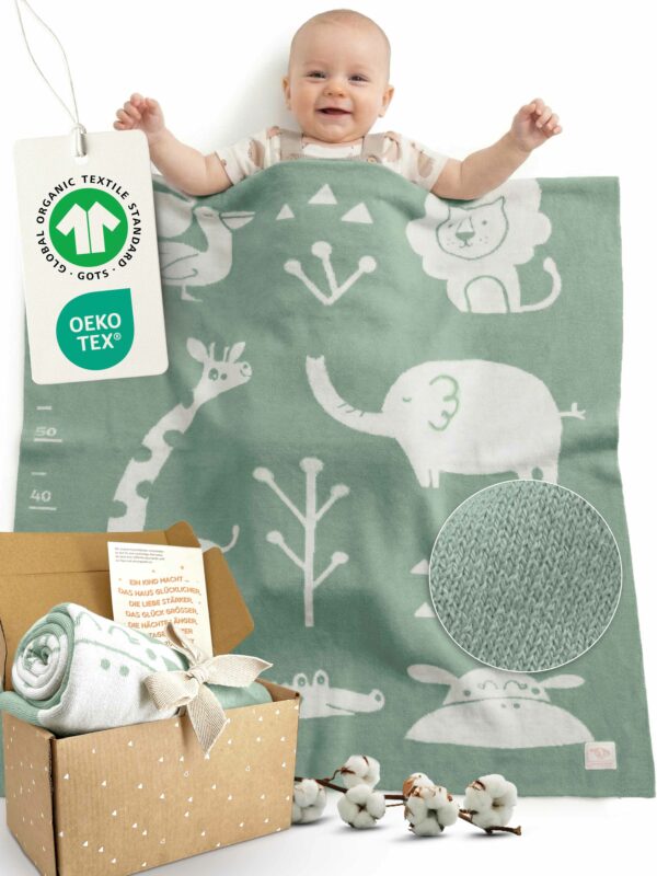 Glückliches Baby liegt unter gestrickter Babydecke, Weiche Babydecke aus Baumwolle in Grün – hochwertige Bio Baumwolle Babydecke mit OEKO-TEX und GOTS Zertifizierung, ideales Geschenk für Neugeborene.
