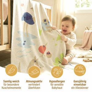 Baby spielt mit der Merle Toys Baumwoll Babydecke im Kinderzimmer, während die Bio Babydecke Savannenfreunde als samtig weich, atmungsaktiv und ganzjährig nutzbar präsentiert wird.