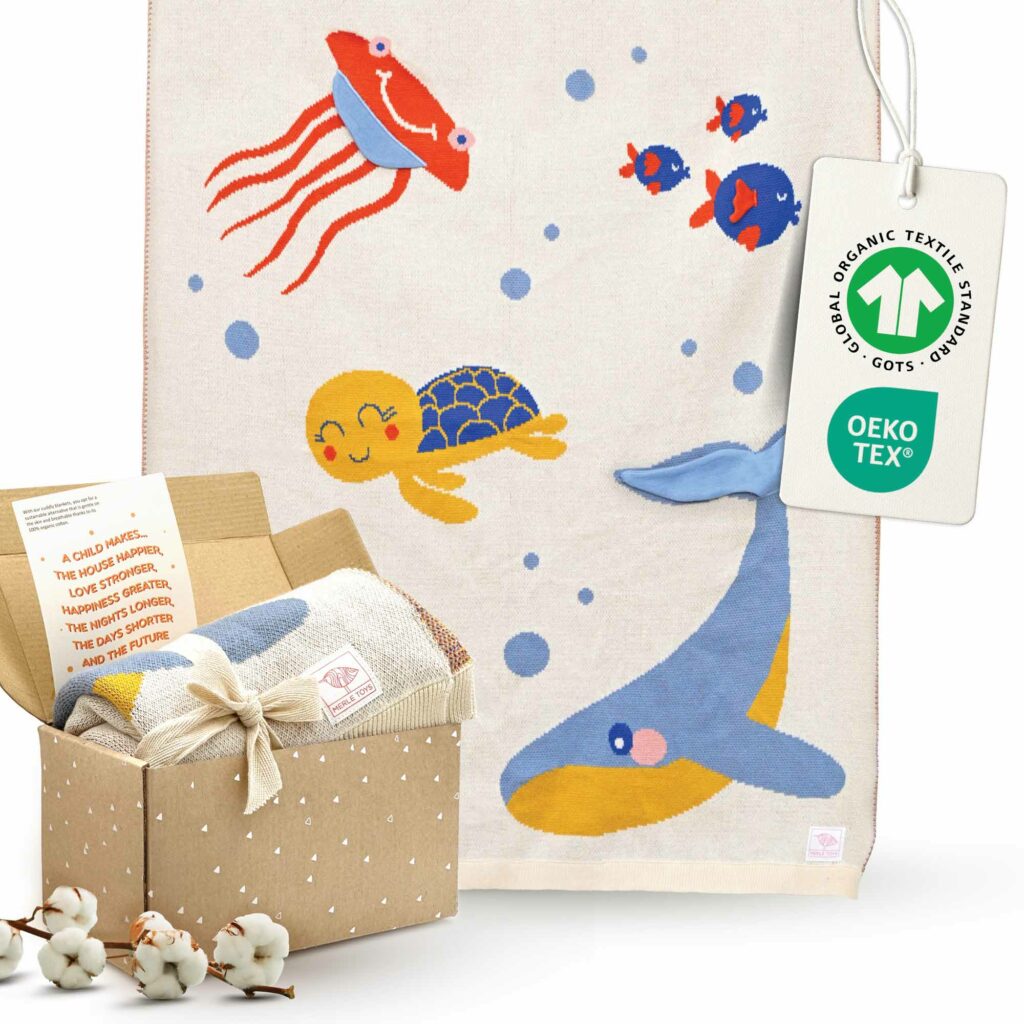 Die Merle Toys Baumwoll babydecke im Design Meereswelt ist als gestrickte Babydecke in einer liebevollen Geschenkbox mit Grußkarte verpackt und eignet sich wunderbar als Geschenk zur Taufe Mädchen.