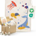 Die Merle Toys Baumwoll babydecke im Design Meereswelt ist als gestrickte Babydecke in einer liebevollen Geschenkbox mit Grußkarte verpackt und eignet sich wunderbar als Geschenk zur Taufe Mädchen.