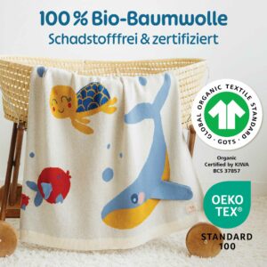 Die Merle Toys Baumwoll babydecke Meereswelt hängt dekorativ am Stubenwagen und zeigt als gestrickte Babydecke aus Bio-Baumwolle ihre zertifizierte, schadstofffreie Qualität.