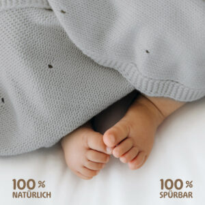 Babyfüße unter grauer Babydecke Strick von Merle Toys – natürliche Materialien und sanft zur Haut.