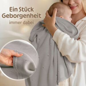 Mutter hält schlafendes Baby in einer grauen Babydecke Strick von Merle Toys – kuschelig und weich für Geborgenheit unterwegs.