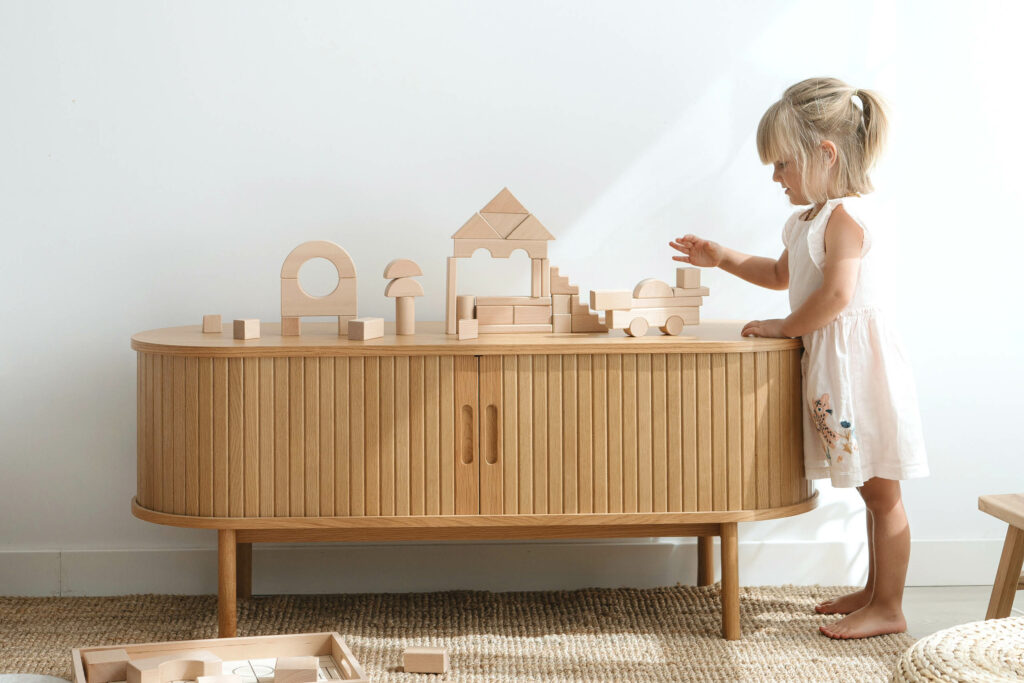 Montessori Holzspielzeug: Mädchen stapelt Holzklötze – pädagogisches Holzspielzeug für Kinder zur Förderung der Motorik