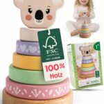 Stapelturm Baby von Merle Toys mit Koalakopf, fünf pastellfarbenen Holzringen, FSC-Anhänger, Verpackung und lachendem Kind im Hintergrund, liebevolles Holz Spielzeug Baby und Holz Stapelspiel