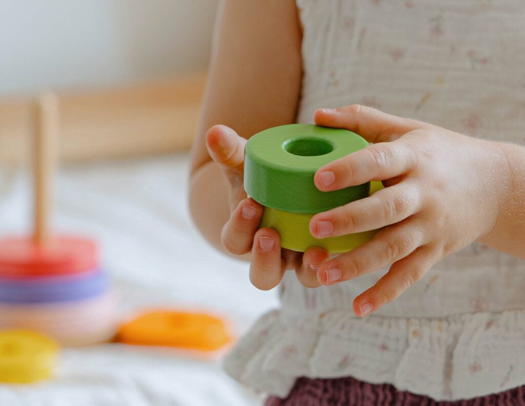 Kleines Kind spielt mit einem Montessori Spielzeug (Stapelturm) von Merle Toys