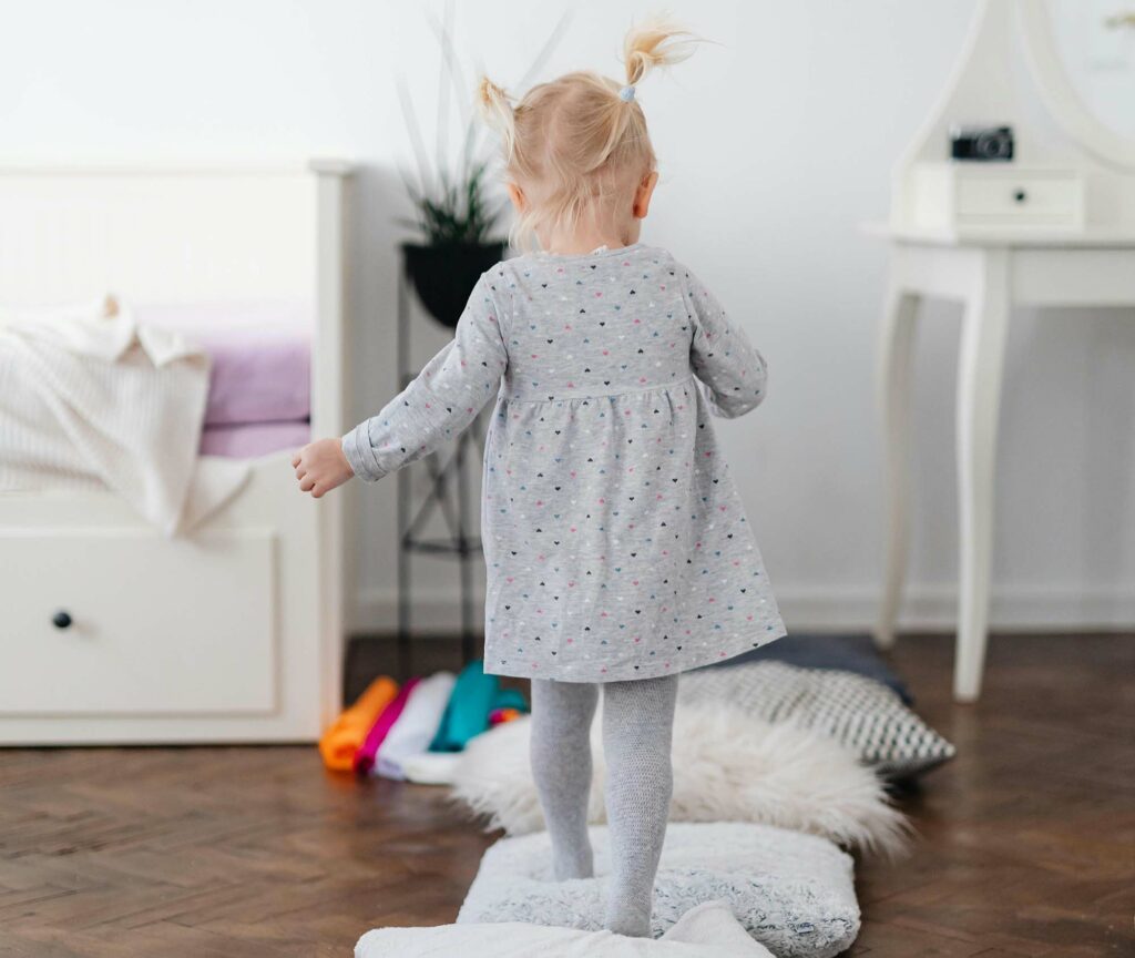 Grobmotorik erlernen und üben funktioniert spielerisch zu Hause - zum Beispiel beim Laufen und Klettern über Kissen. Das stärkt die Balance und Körperwahrnehmung.