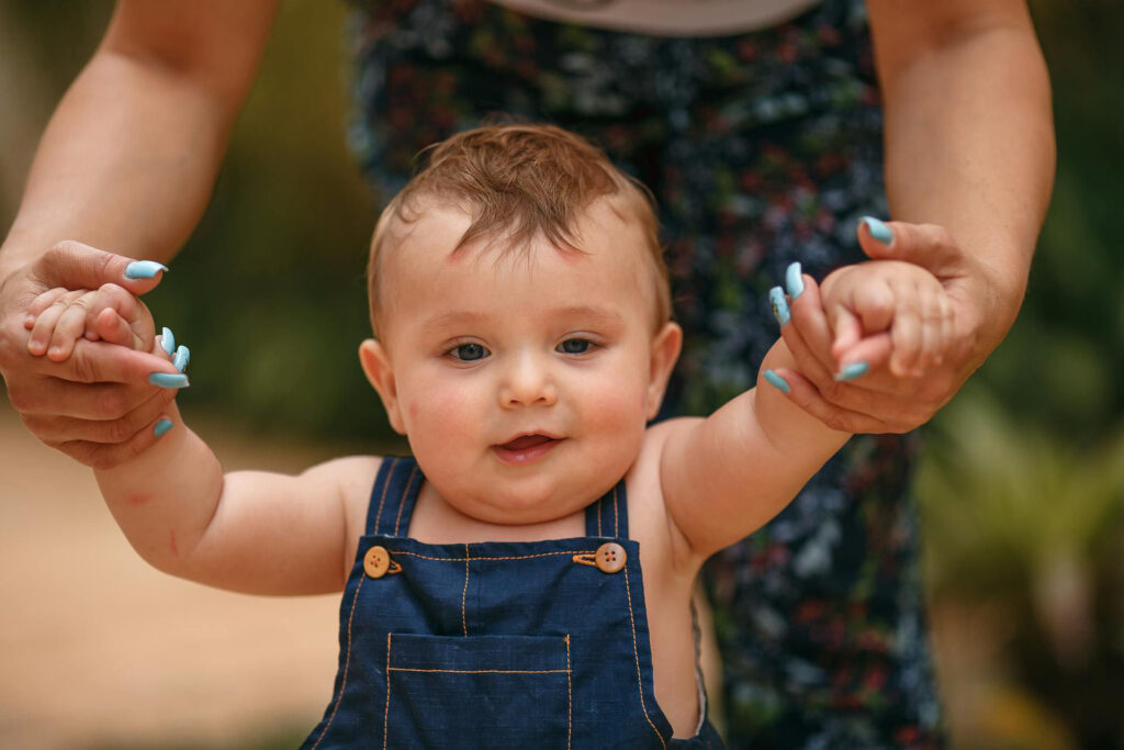 Ein Baby lernt, mit der Unterstützung der Mutter, zu laufen und macht seine ersten Schritte.