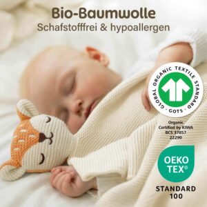Ein schlafendes Baby liegt zugedeckt mit der Merle Toys Baby Kuscheldecke Beige und kuschelt neben dem weichen Fuchsköpfchen. Die Knuddeldecke wird mit GOTS und OEKO TEX Zertifizierung gezeigt und eignet sich als Kuscheldecke Babys, Bio Baumwoll Babydecke Winter und Decke für Kinderwagen.