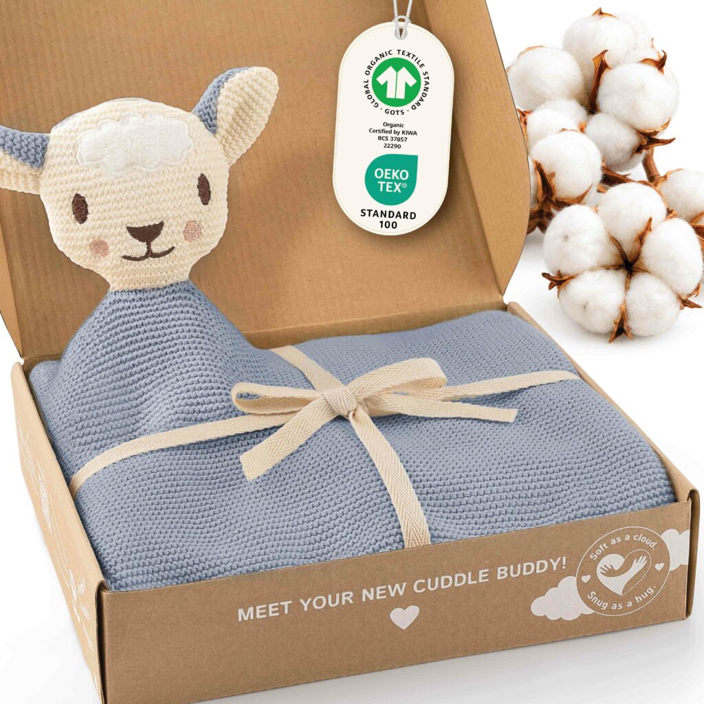Geöffnete Geschenkbox mit der hellblauen Merle Toys_Baby Kuscheldecke Babys, integriertem Schafsköpfchen, Schleife sowie GOTS und OEKO TEX Kennzeichnung. Die Bio Baumwoll Babydecke gehört zu den weichen Knuddeldecken und eignet sich als Decke für Kinderwagen, für Winter und Sommer sowie als Kuscheldecke Baby Junge.