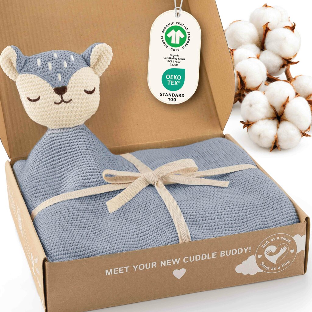 Geöffnete Geschenkbox mit der blauen Merle Toys_Baby Kuscheldecke Babys, integriertem Fuchsköpfchen, Schleife sowie GOTS und OEKO TEX Kennzeichnung. Die weiche Bio Baumwoll Babydecke gehört zu den kuscheligen Knuddeldecken für Winter und Sommer und eignet sich als Decke für Kinderwagen und Kuscheldecke Baby Junge.