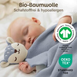 Ein schlafendes Baby liegt zugedeckt mit der blauen Merle Toys_Baby Kuscheldecke Babys und kuschelt neben dem weichen Fuchsköpfchen. Die Bio Baumwoll Babydecke wird mit GOTS und OEKO TEX Zertifizierung gezeigt und eignet sich als eine der Knuddeldecken für Winter und Sommer, als Decke für Kinderwagen und Kuscheldecke Baby Junge.