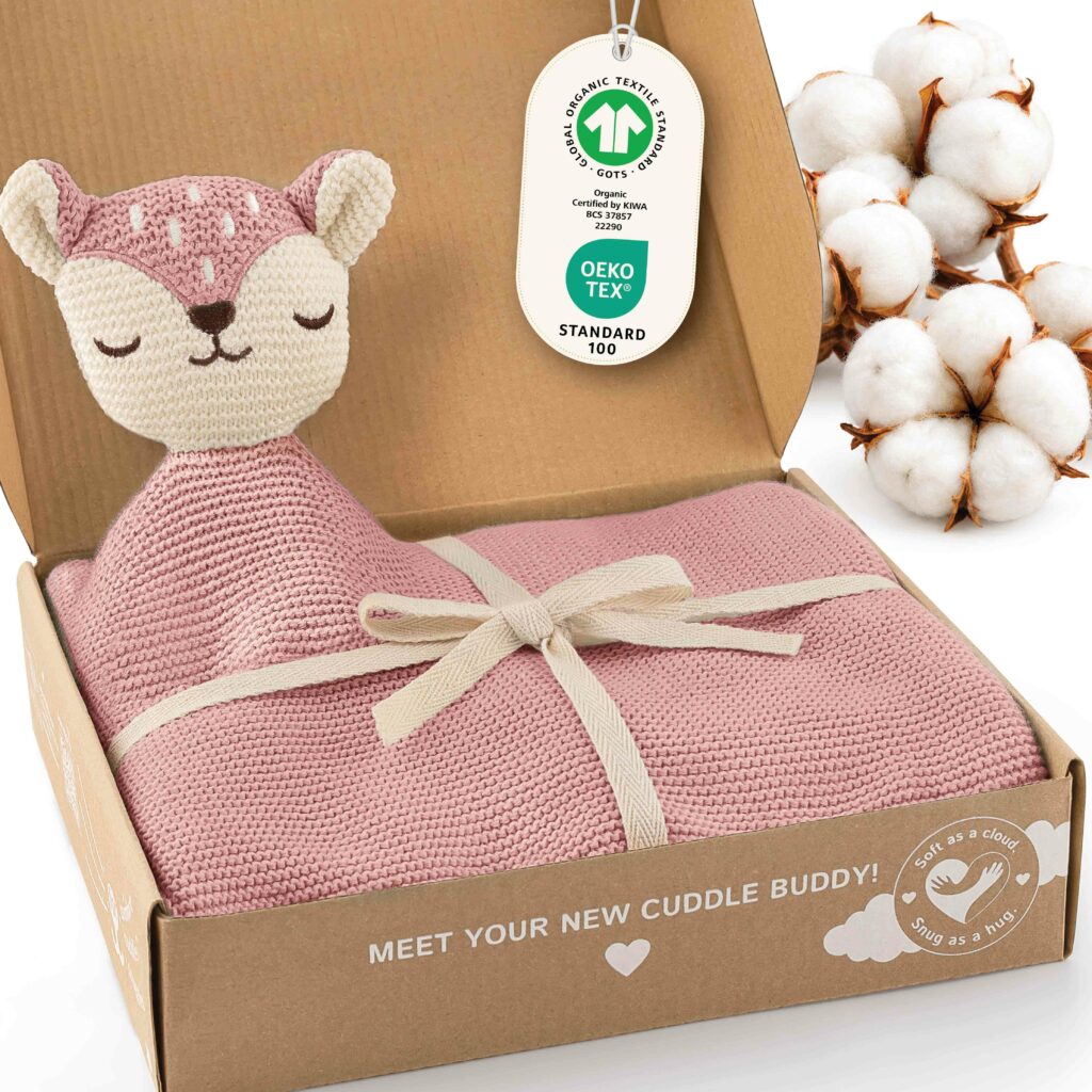 Geöffnete Geschenkbox mit der rosa Merle Toys_Knuddeldecke, integriertem Fuchsköpfchen, Schleife sowie GOTS und OEKO TEX Kennzeichnung. Die Baby Kuscheldecke Mädchen ist eine weiche Babydecke Strick aus Baumwolle und eignet sich als Baumwoll Babydecke Winter, Kuscheldecke Baby und Geschenk für Neugeborene.
