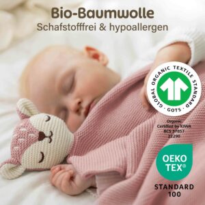 Ein schlafendes Baby liegt zugedeckt mit der rosa Merle Toys_Knuddeldecke und kuschelt neben dem weichen Fuchsköpfchen. Die Baby Kuscheldecke Mädchen aus Bio Baumwolle wird mit GOTS und OEKO TEX Zertifizierung gezeigt und eignet sich als Babydecke Strick, Baumwoll Babydecke Winter, Kuscheldecke Baby und Geschenk für Neugeborene.